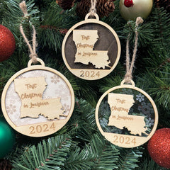 Louisiana-shaped First Christmas in Louisiana ornament hanging on a festive holiday tree with twinkling lights and lush greenery. A perfect keepsake to celebrate a lively first Christmas in the Pelican State, capturing its unique culture and vibrant holiday spirit.