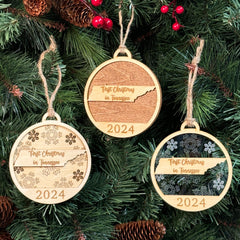 Tennessee-shaped First Christmas in Tennessee ornament hanging on a festive holiday tree with twinkling lights and evergreen branches. A perfect keepsake to celebrate a memorable first Christmas in the Volunteer State, capturing its southern charm and musical heritage.