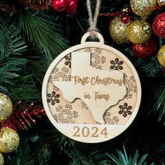 Texas-shaped First Christmas in Texas ornament hanging on a glowing holiday tree with twinkling lights and festive greenery. A perfect keepsake to celebrate a memorable first Christmas in the Lone Star State, reflecting its bold spirit and warm holiday cheer.